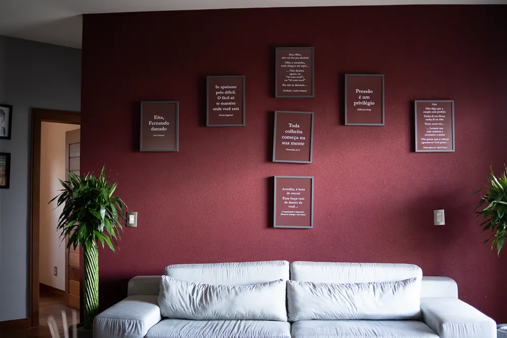 Parede vinho com quadros de frases sobre um sofá branco