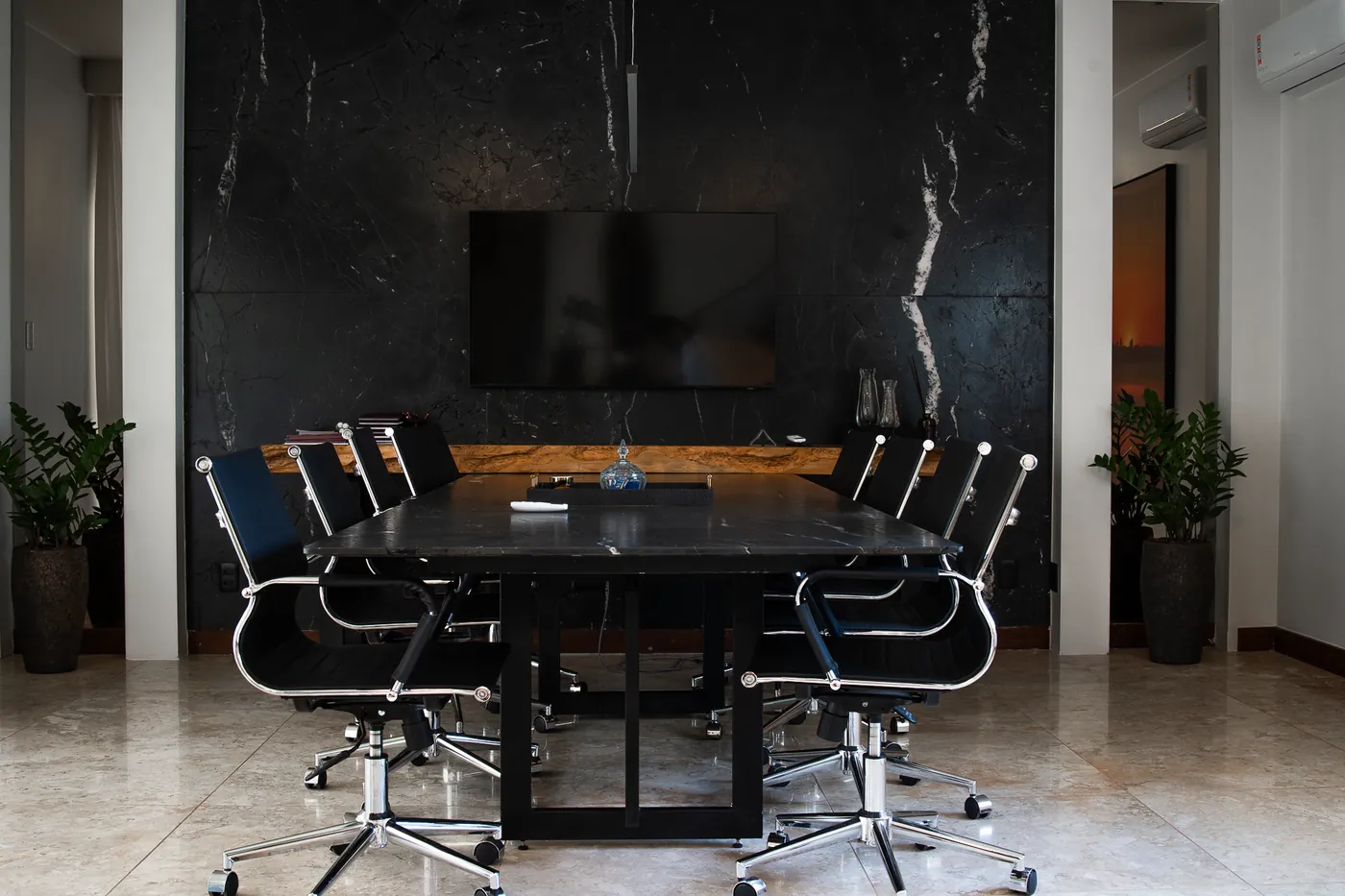 Sala de reuniões com mesa e parede de mármore escuro