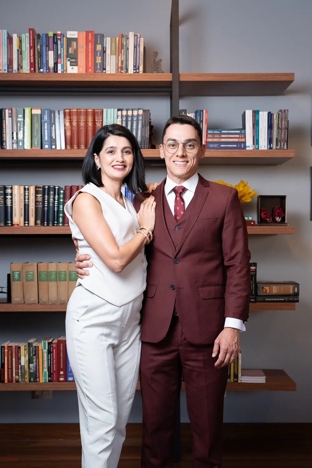 Dois integrantes da equipe diante da estante de livros